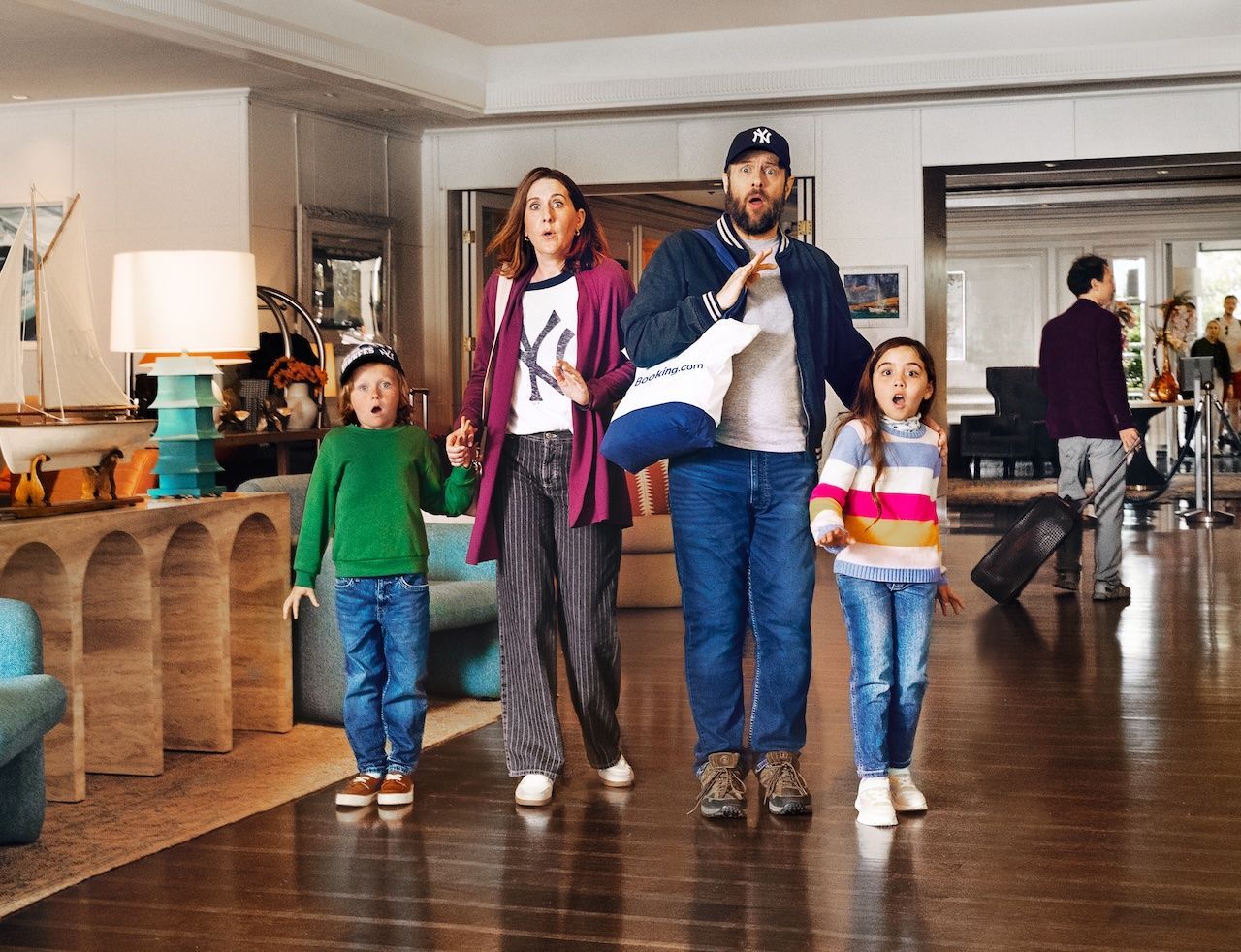 A son, mother, father and daughter stand in a room looking shocked