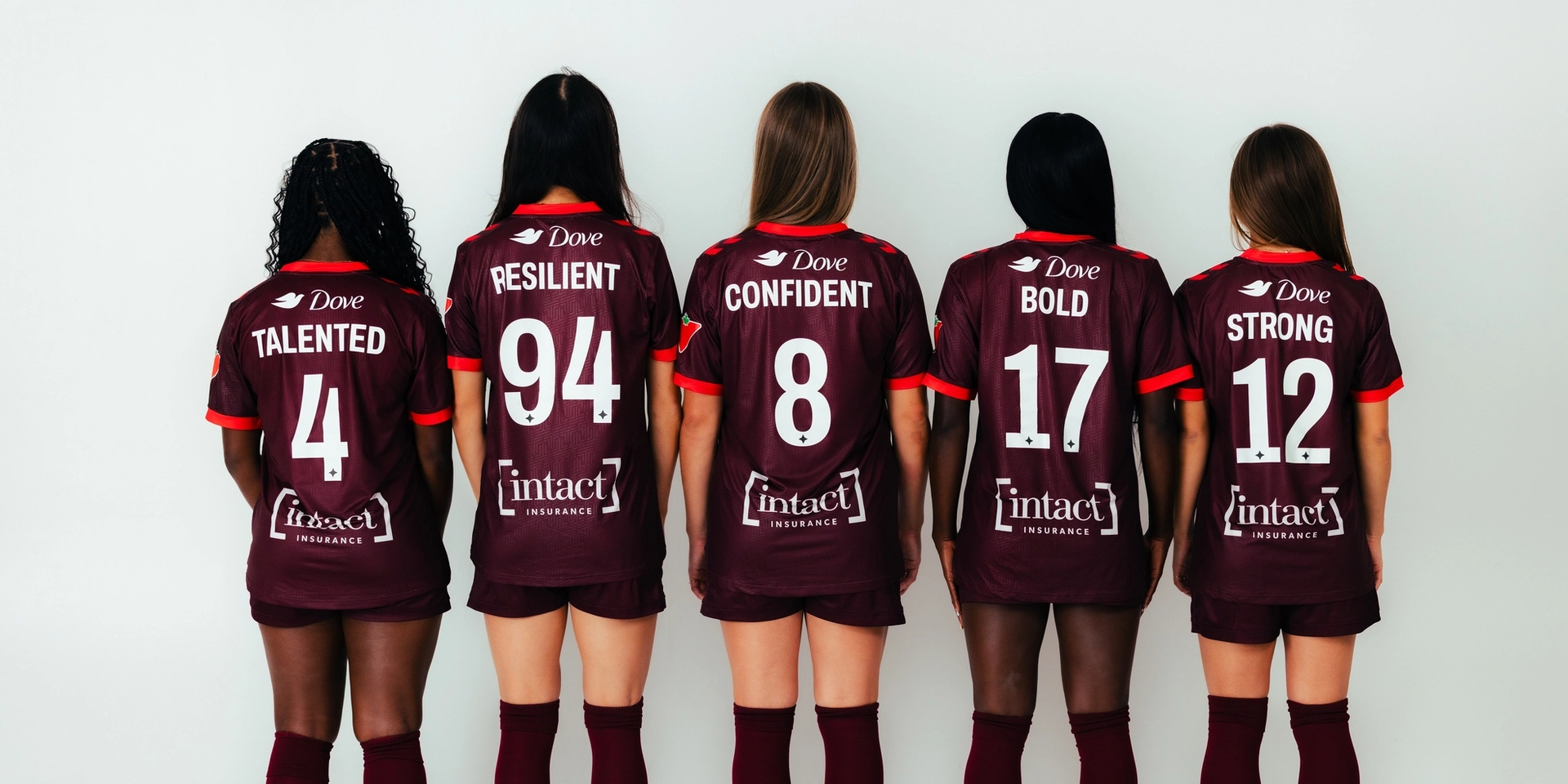 Five women stand facing away, wearing maroon soccer jerseys with words
