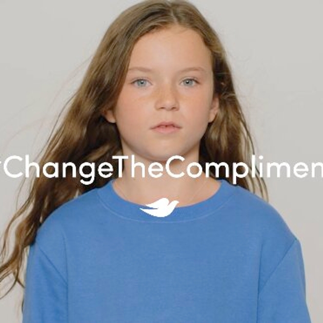 Young girl with long hair in a blue shirt, looking calmly at the camera. The text "#ChangeTheCompliment" is overlaid, promoting positive change.