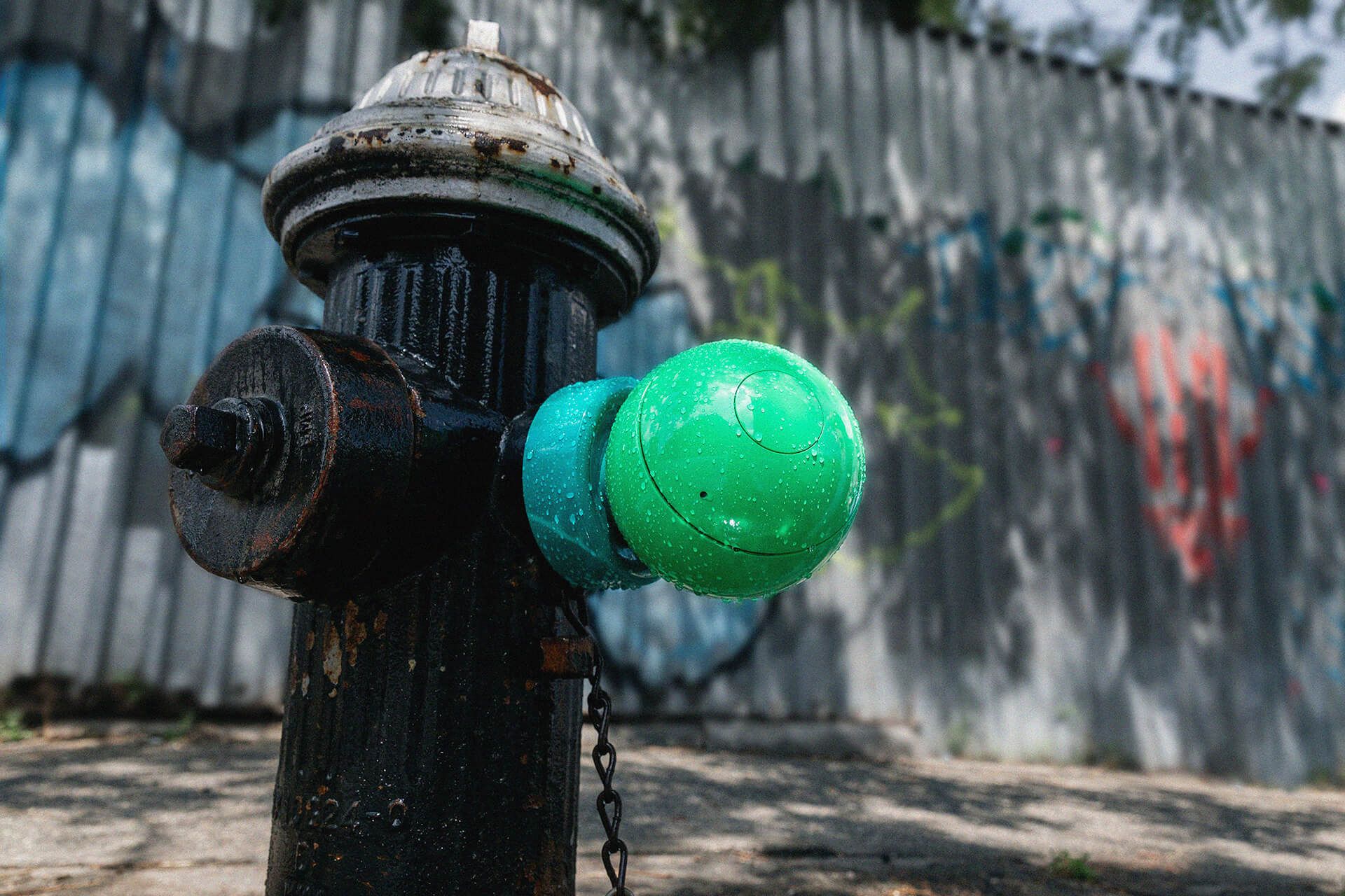 An old fire hydrant with a bright green Splash Spot hydrant cap on the streets of New York. 