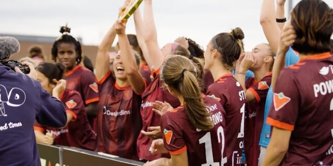 A joyous soccer team in maroon jerseys celebrates a victory. One player lifts a trophy, while teammates cheer and smile energetically, capturing a moment of triumph.