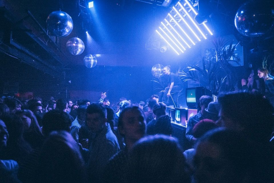 Crowd dancing under atmospheric blue stage lighting at a club show during ADE week