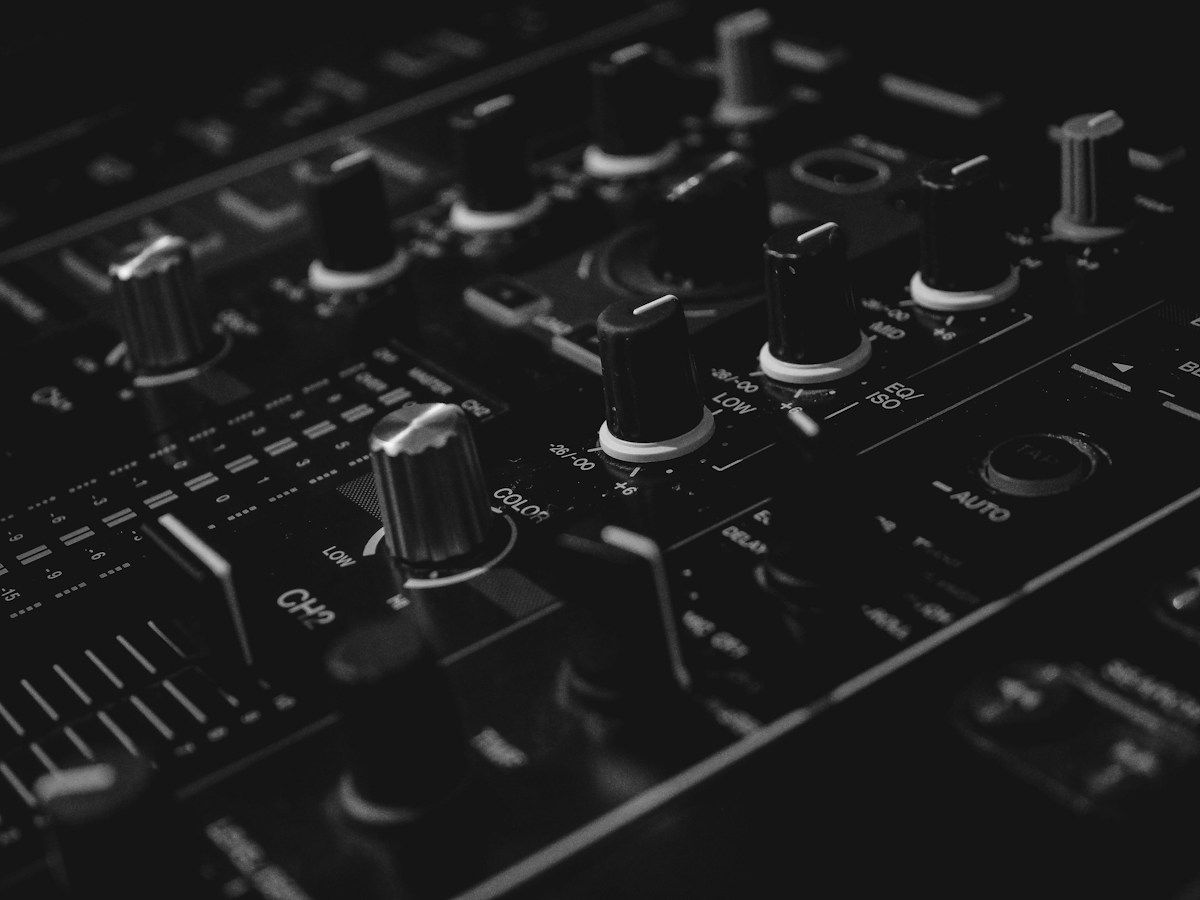 Close-up of a professional DJ mixer showing EQ knobs, channel faders, and controls