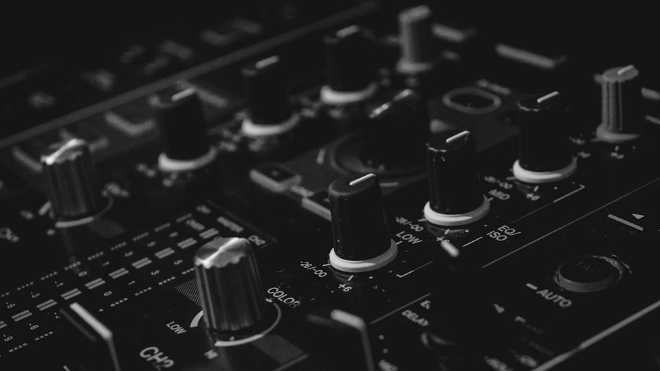 Close-up of a professional DJ mixer showing EQ knobs, channel faders, and controls