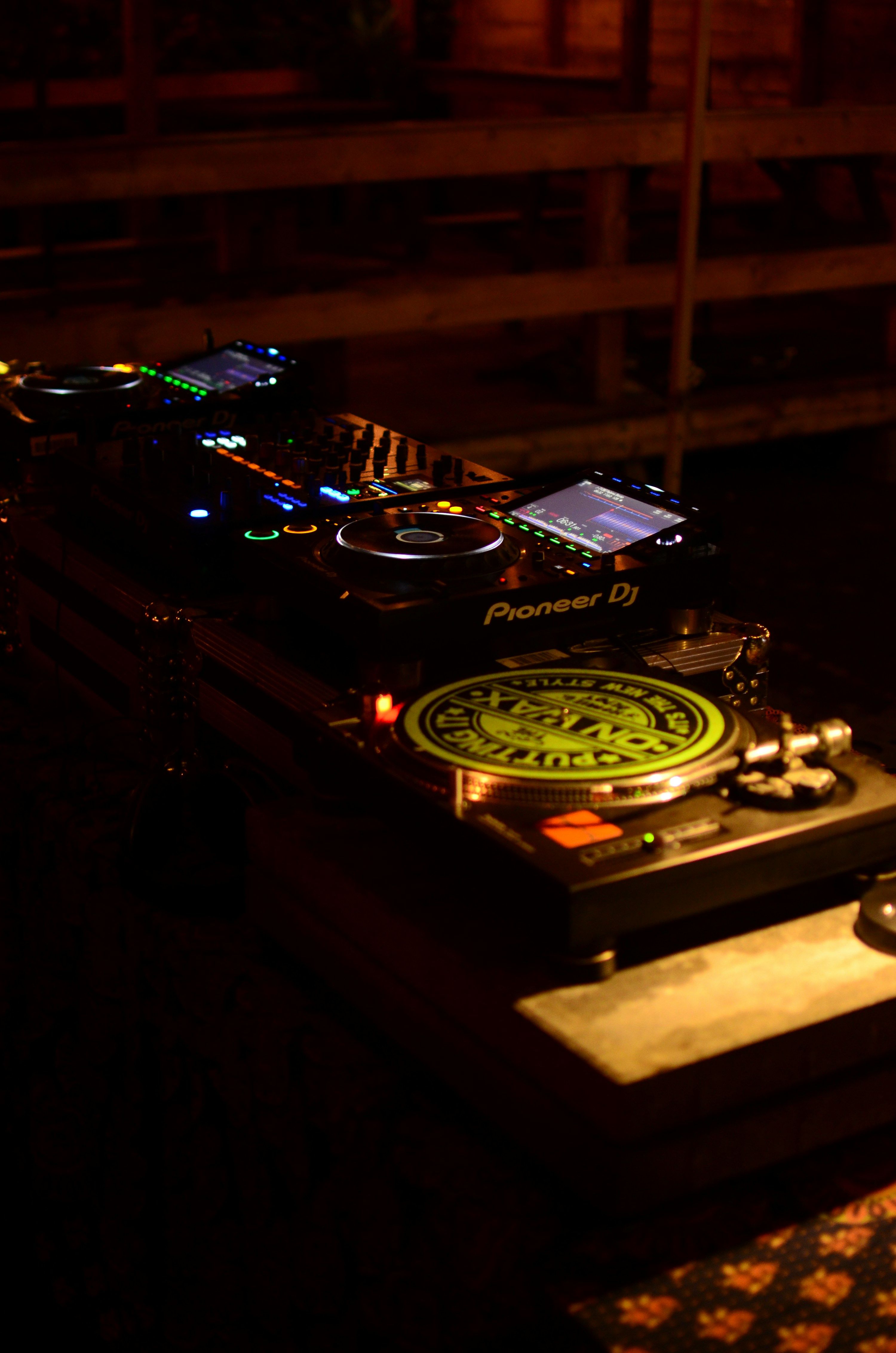 A DJ performing in atmospheric dark lighting at an intimate venue
