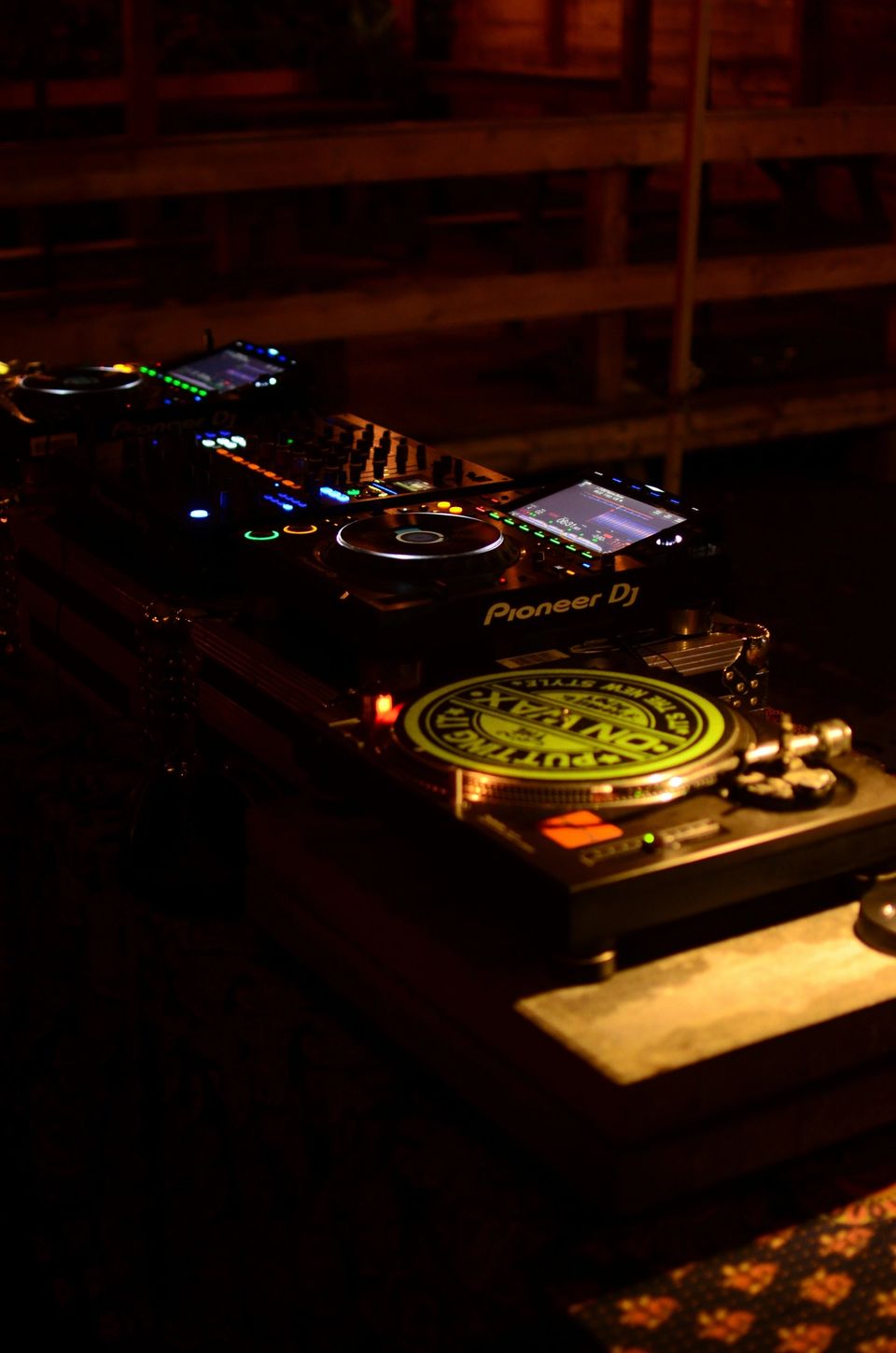 A DJ performing in atmospheric dark lighting at an intimate venue