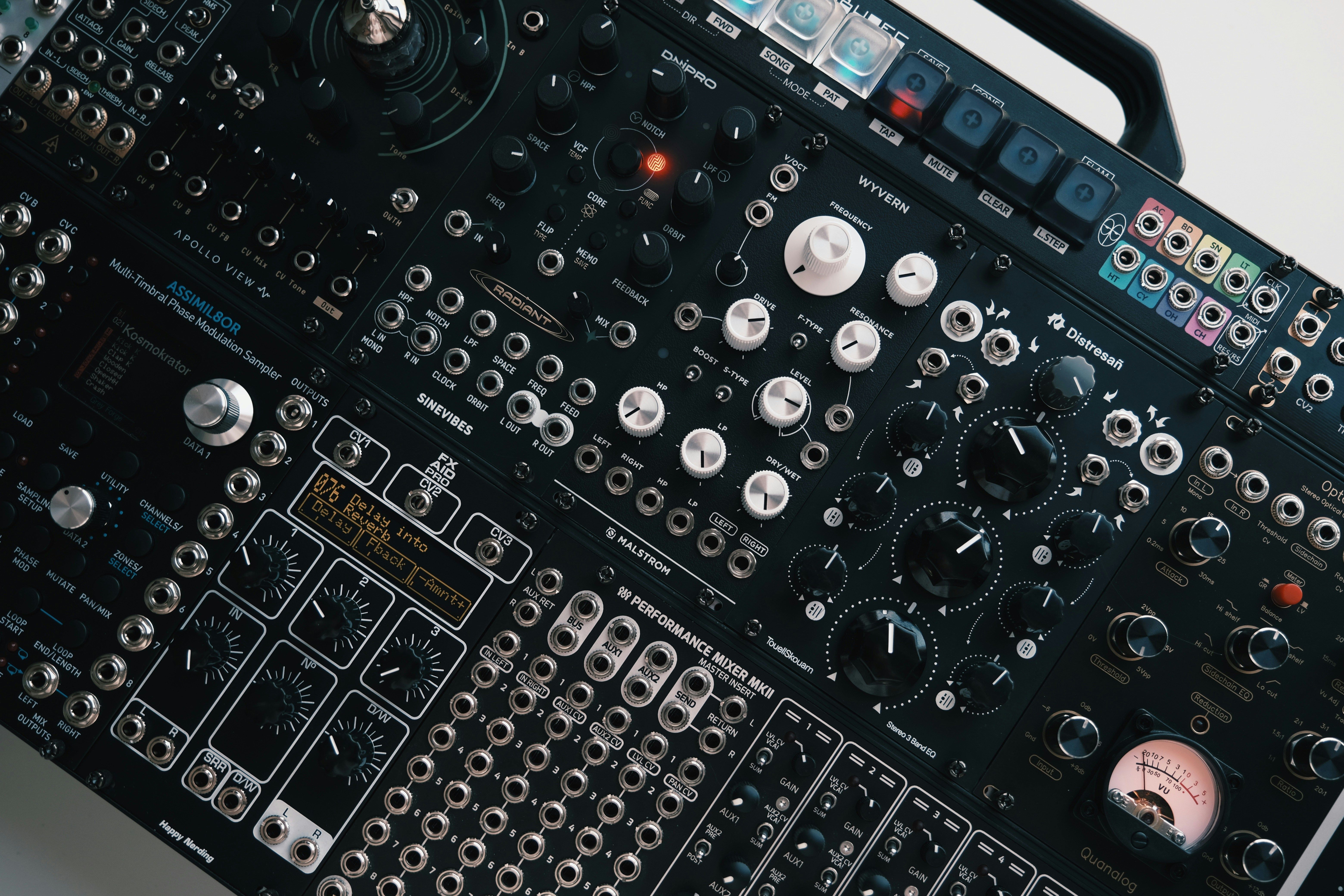 Close-up of a modular synthesizer panel with patch cables and knobs in dark studio light