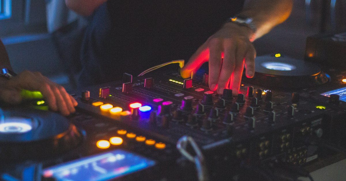 An iPhone resting on a Pioneer DJ mixer in a dark DJ booth during a live set