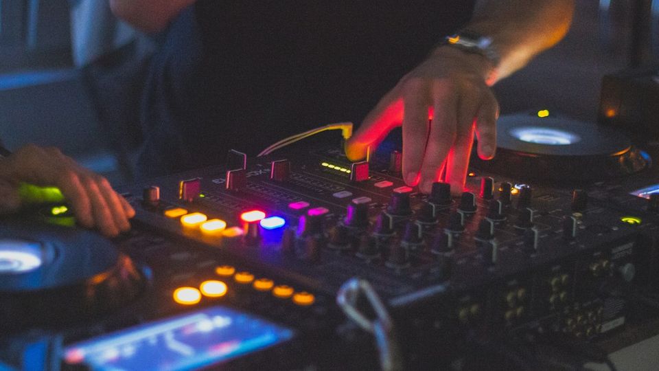 An iPhone resting on a Pioneer DJ mixer in a dark DJ booth during a live set