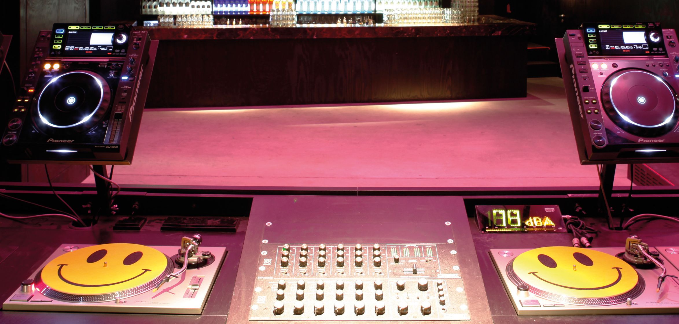 Club DJ booth with a mixer, two turntables and two CDJ players under low light