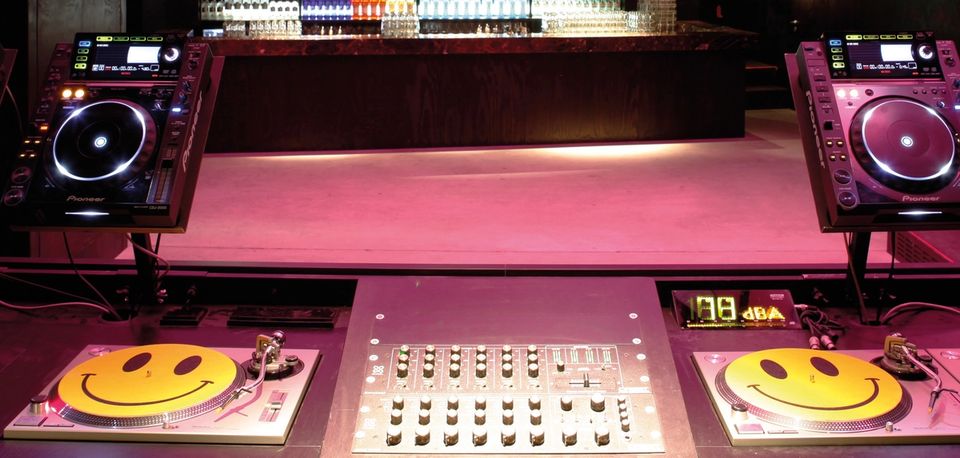 Club DJ booth with a mixer, two turntables and two CDJ players under low light
