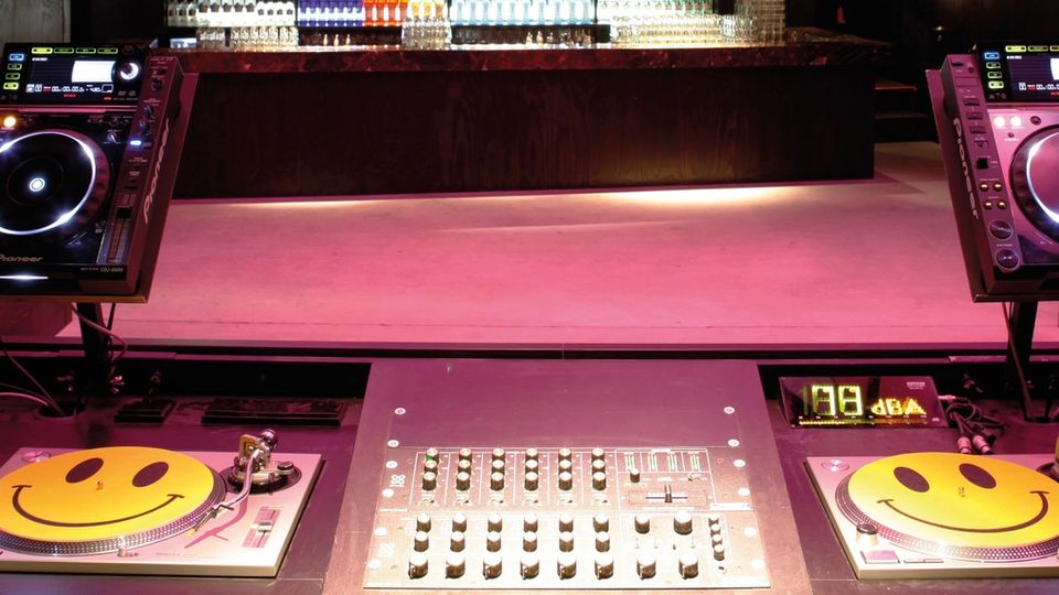 Club DJ booth with a mixer, two turntables and two CDJ players under low light