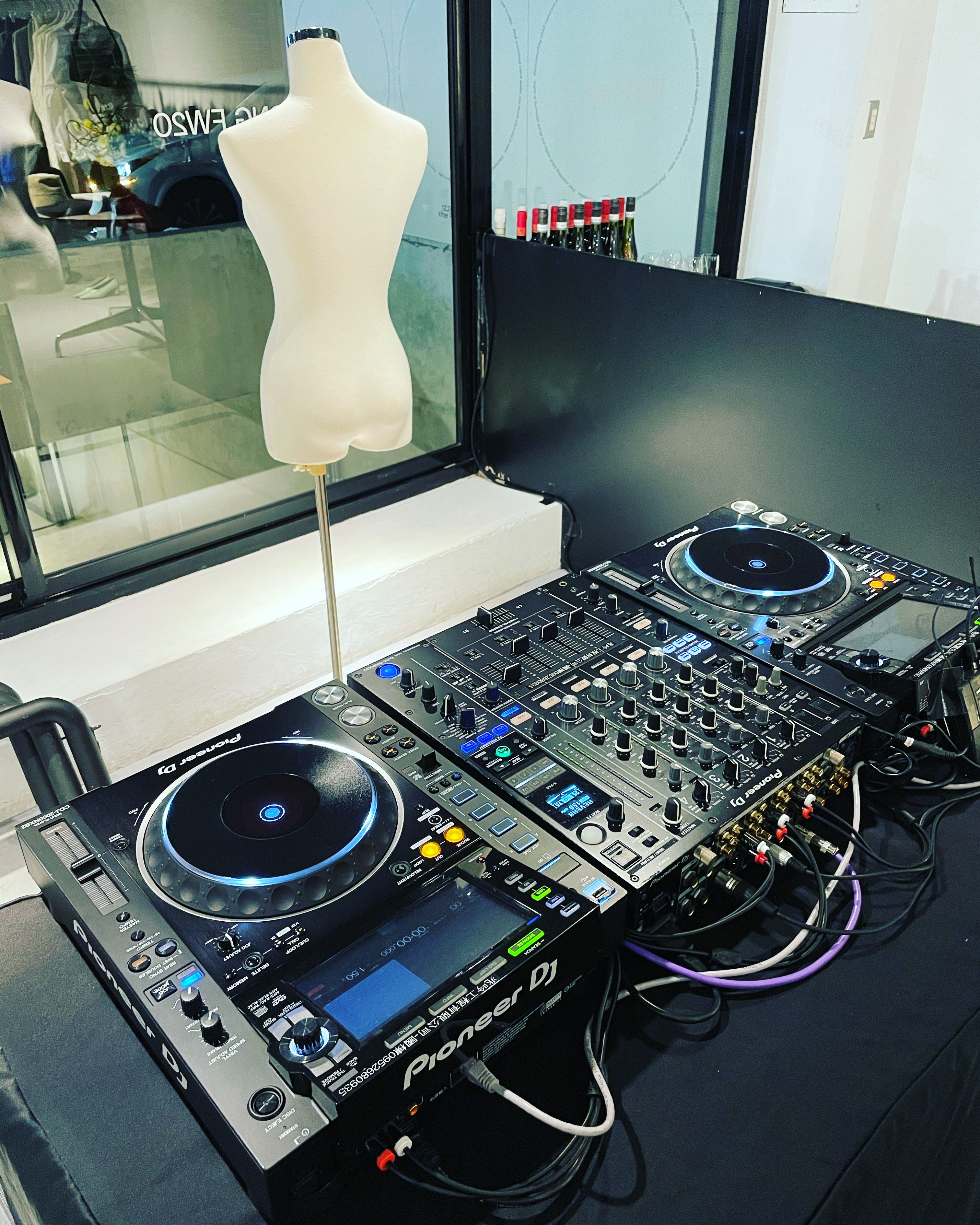 Two Pioneer CDJ-2000NXS2 players either side of a DJM-900NXS2 mixer on a dark table