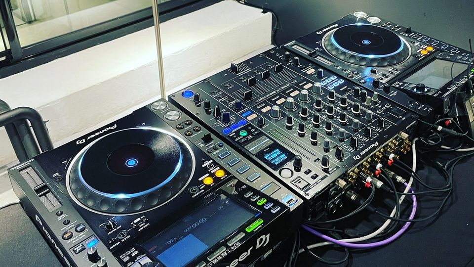 Two Pioneer CDJ-2000NXS2 players either side of a DJM-900NXS2 mixer on a dark table
