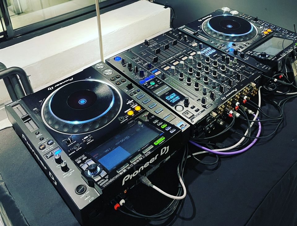 Two Pioneer CDJ-2000NXS2 players either side of a DJM-900NXS2 mixer on a dark table