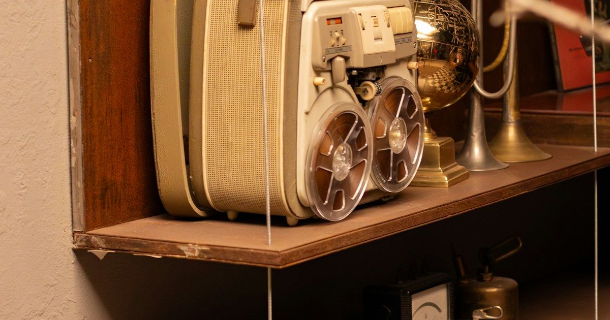 Close-up of a vintage reel-to-reel tape recorder with warm amber tones and analogue grain