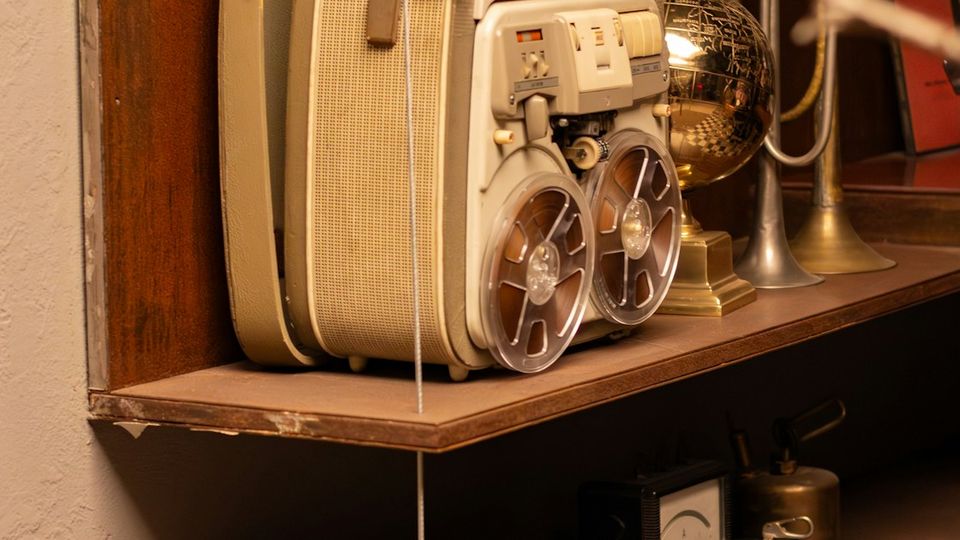Close-up of a vintage reel-to-reel tape recorder with warm amber tones and analogue grain