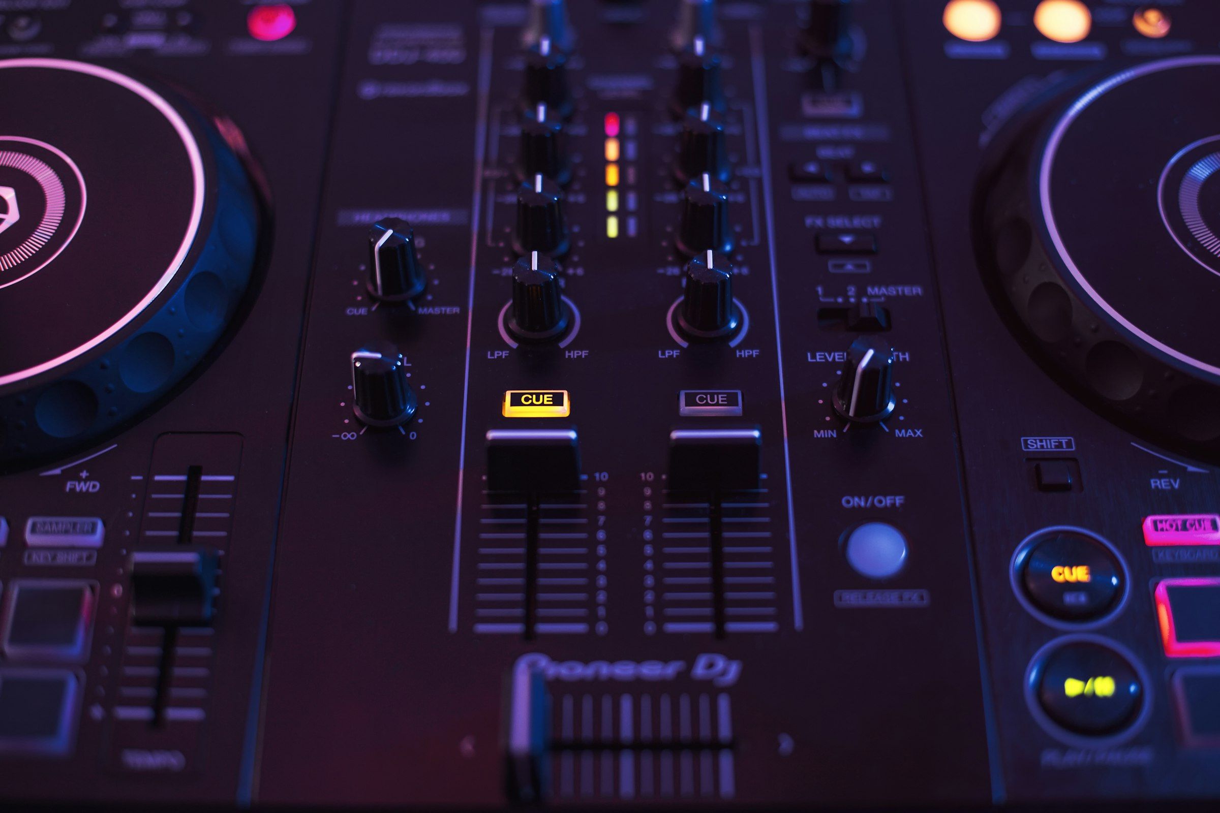 Close-up of a Pioneer DJ controller showing channel faders in dark studio lighting