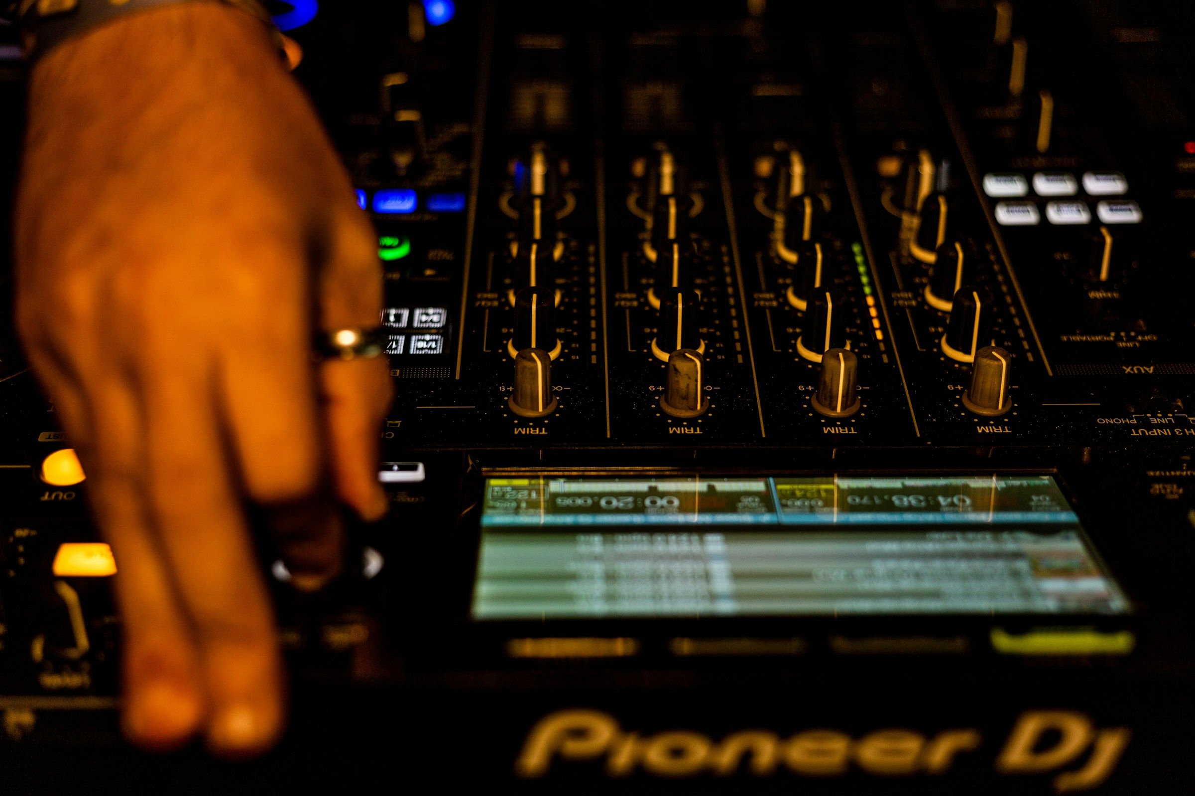 A DJ performing live in a booth with a crowd visible in the background