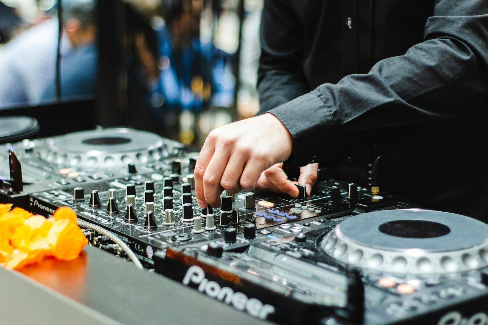 DJ hand adjusting mixer controls on a Pioneer DJ setup during a mix transition