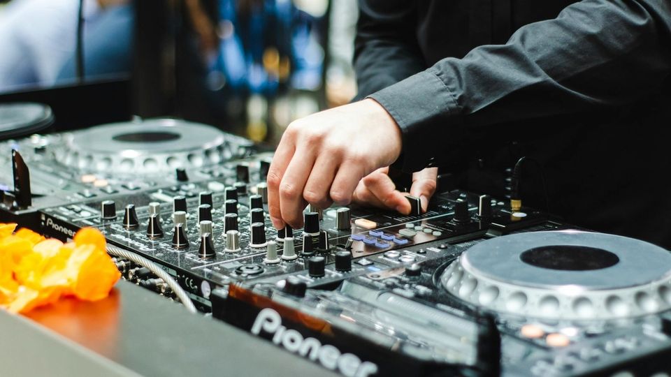 DJ hand adjusting mixer controls on a Pioneer DJ setup during a mix transition