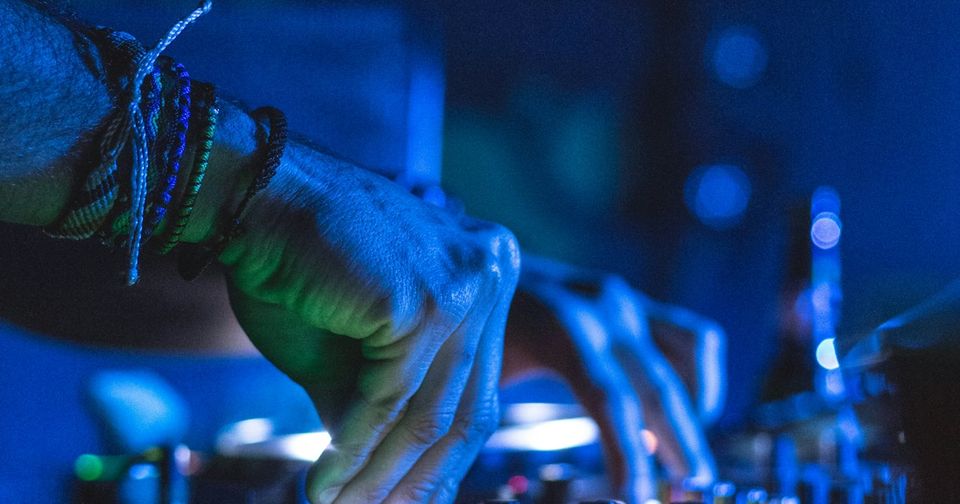 DJ hands on motorized turntable controller platters in a dark studio setting