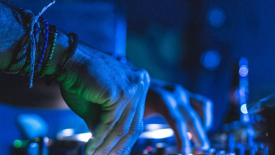 DJ hands on motorized turntable controller platters in a dark studio setting