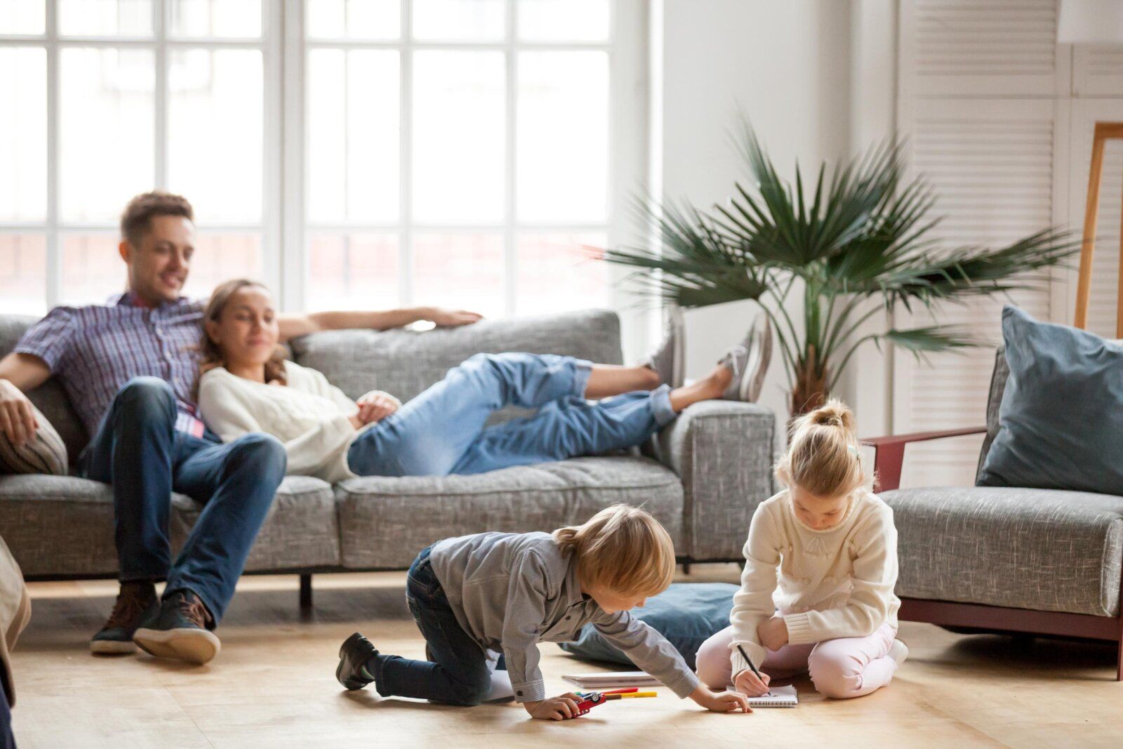 Happy family relaxing in a pest-free living room while children play on the floor