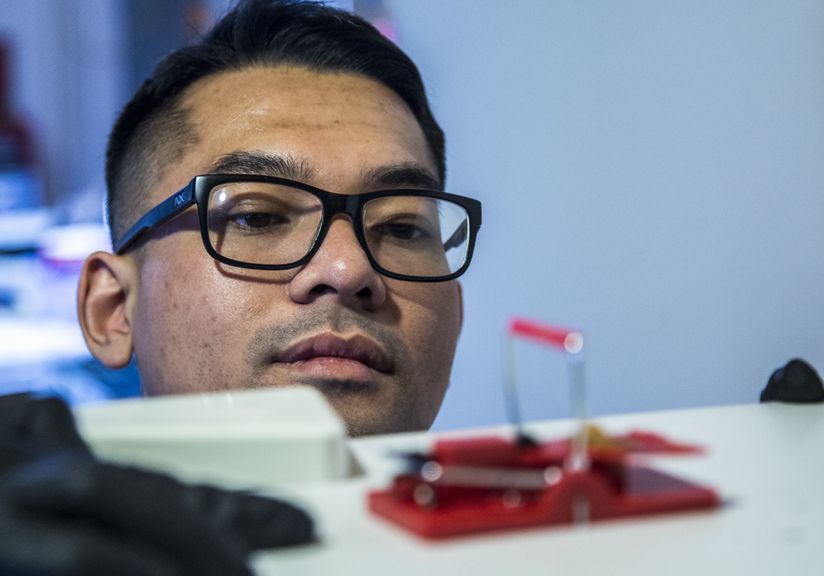 Licensed pest control technician inspecting mouse trap for rodent activity in Minnesota home.