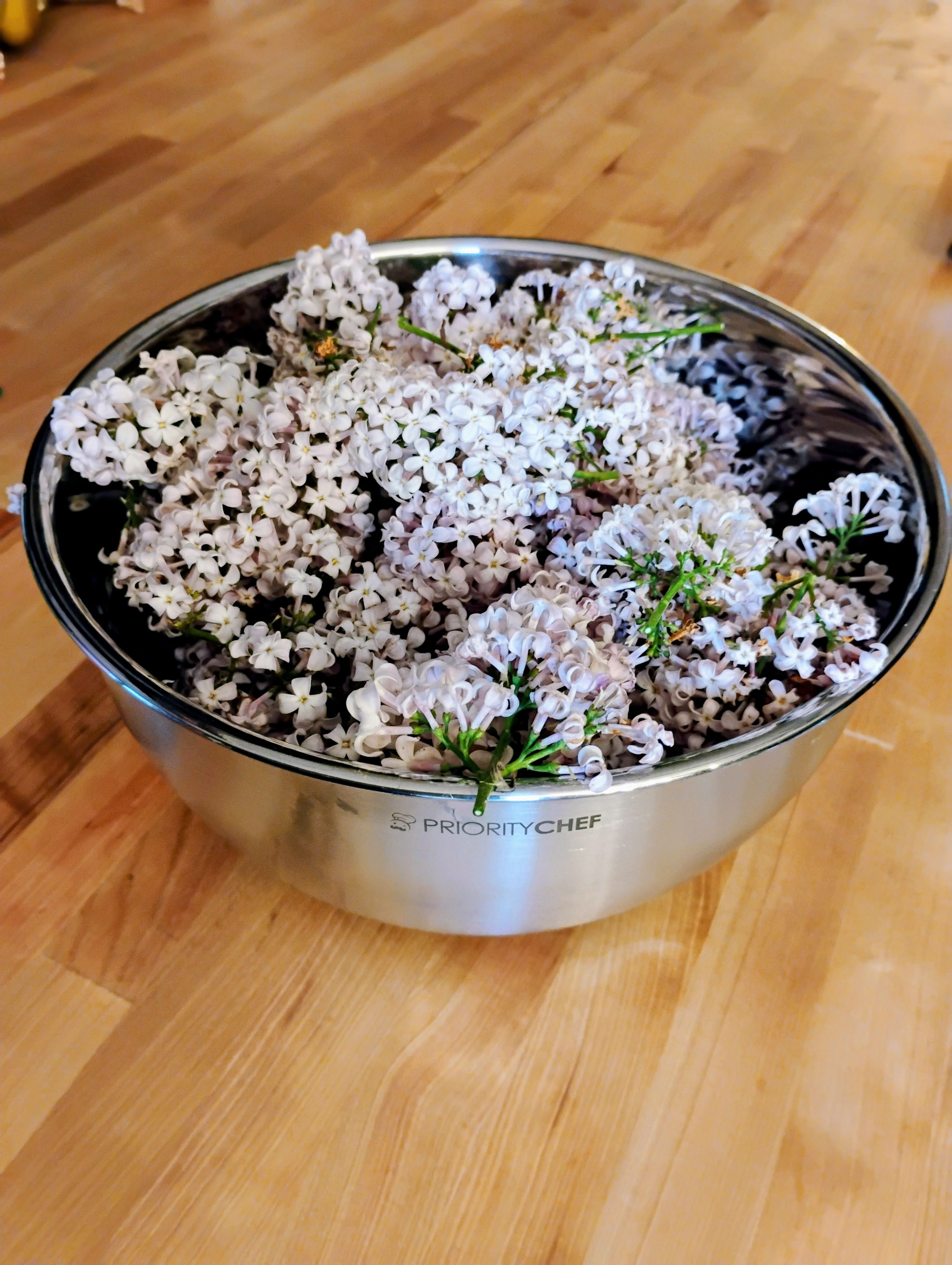 Fresh pale lilac flower clusters in a metal bowl before the individual flowers are pulled.
