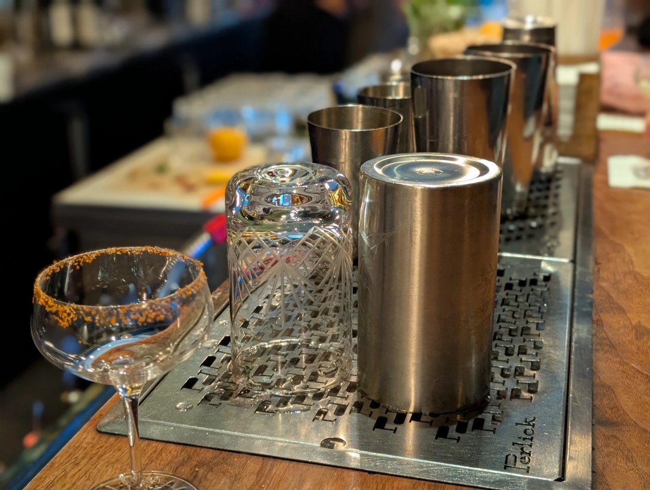 Shaker tins, a patterned mixing glass and a rimmed coupe lined up on The Narrows bar