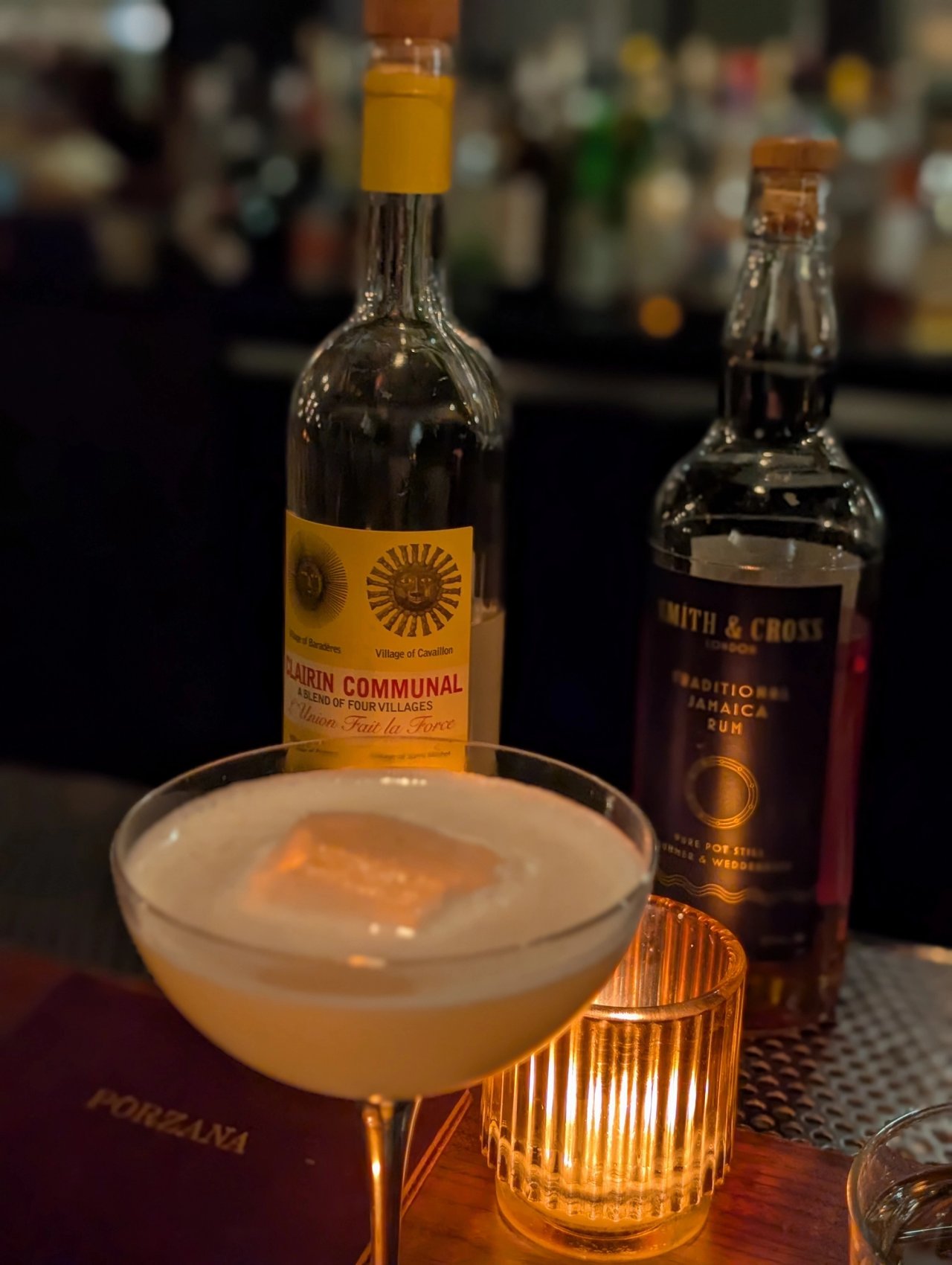 A cocktail in a coupe at Porzana, with bottles of Clairin Communal and Smith & Cross behind it