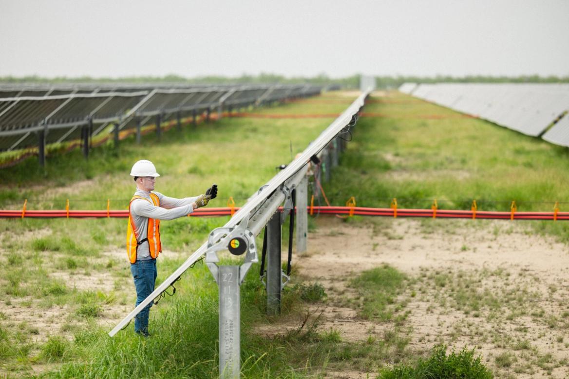 Wide view of solar modules being installed across a field