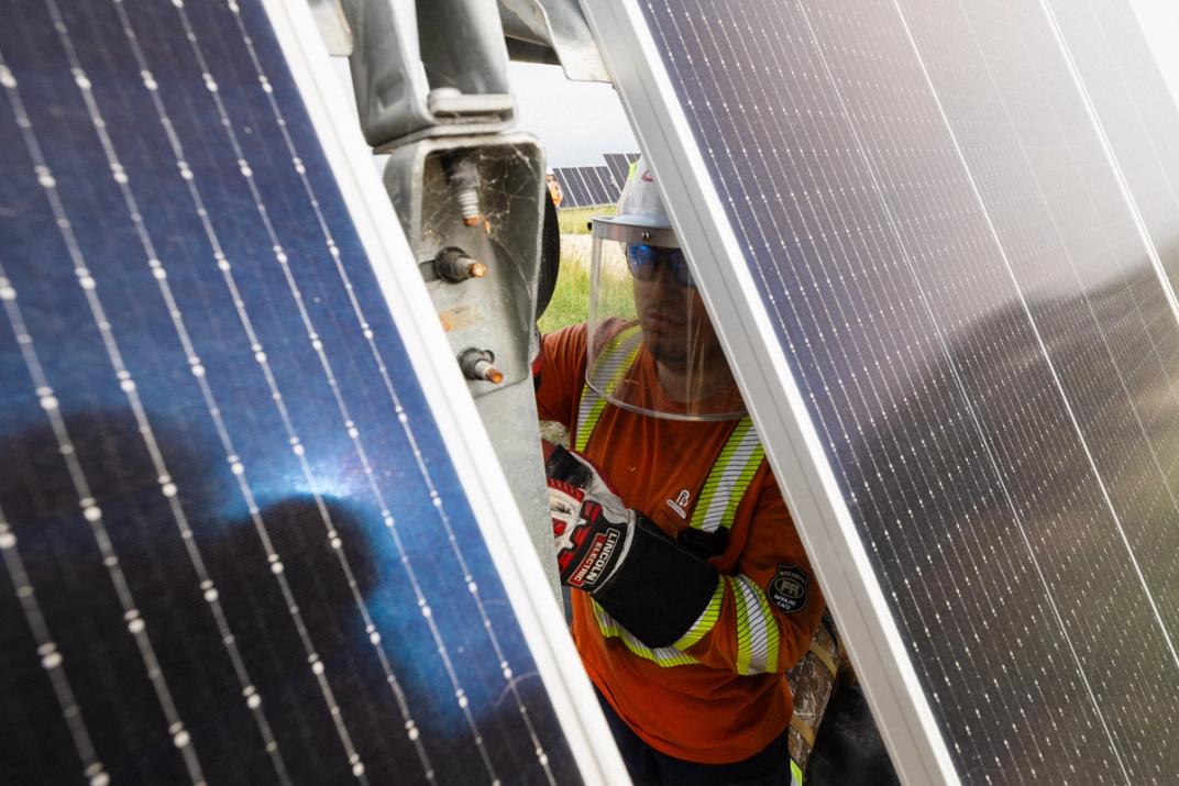 Solar installer carrying a module across a completed array