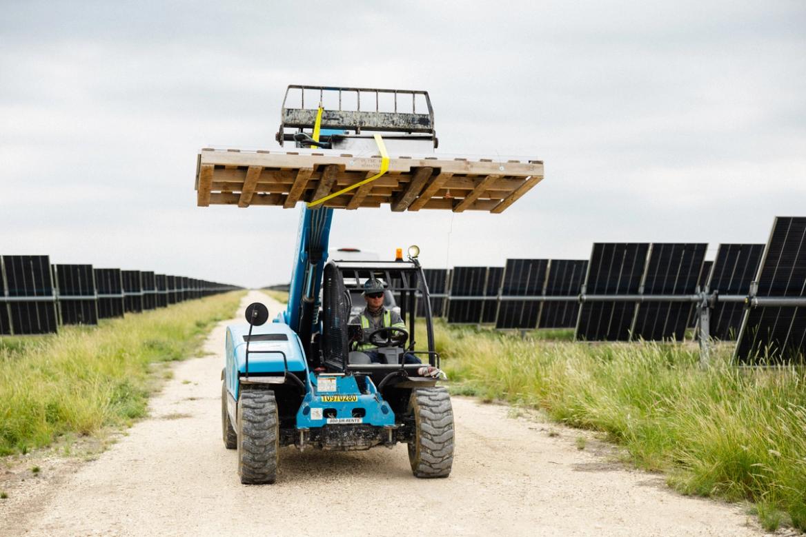 Solar installer working on a utility-scale field at sunset