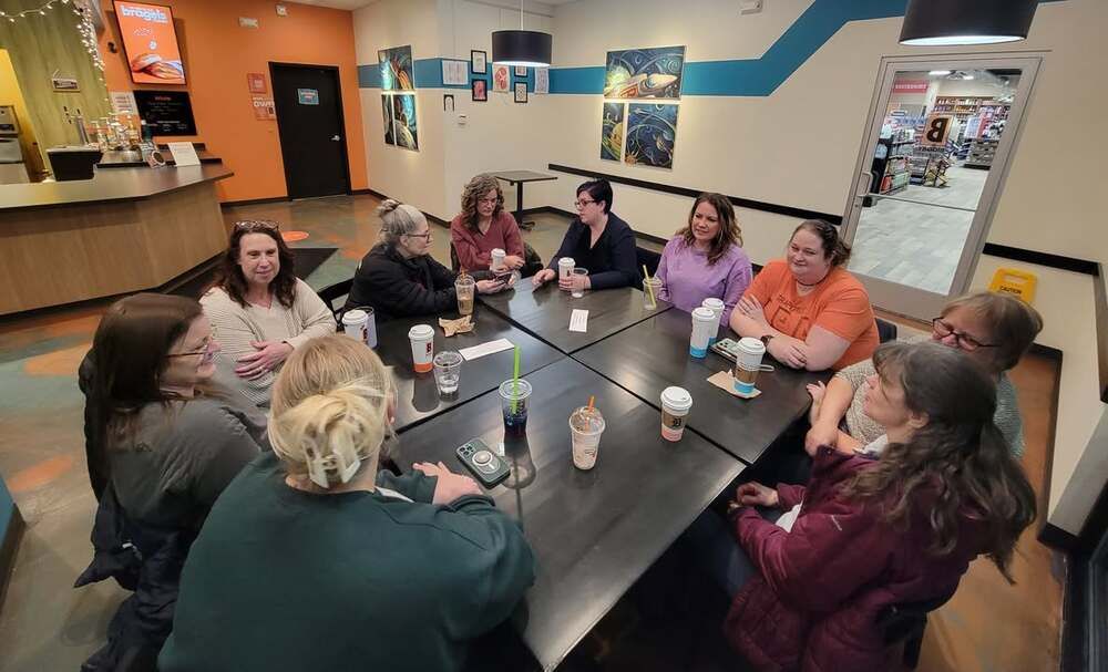 A group of adults talking around a table over coffee