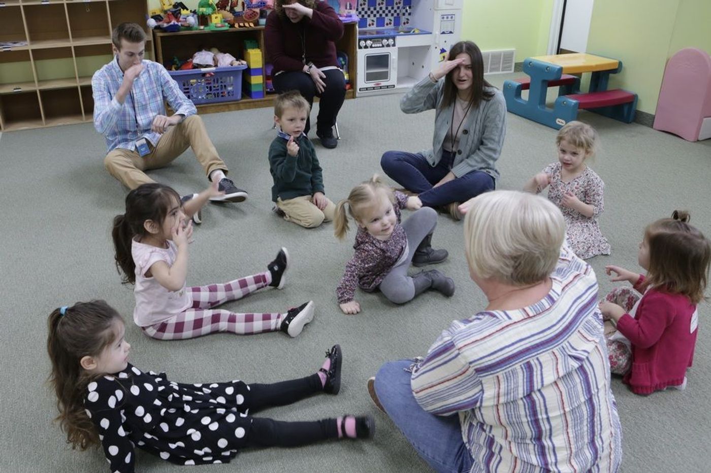 Children and volunteers sitting together in a circle in the GBC Kids room