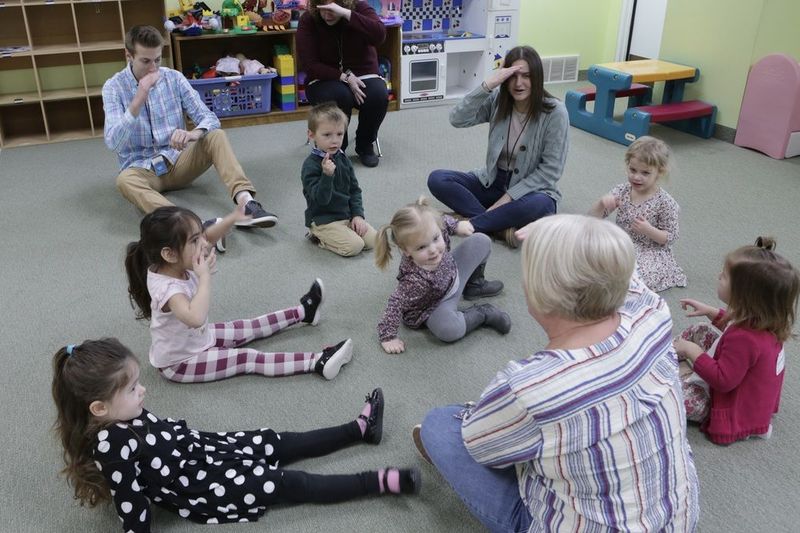 Children and volunteers sitting together in a circle in the GBC Kids room