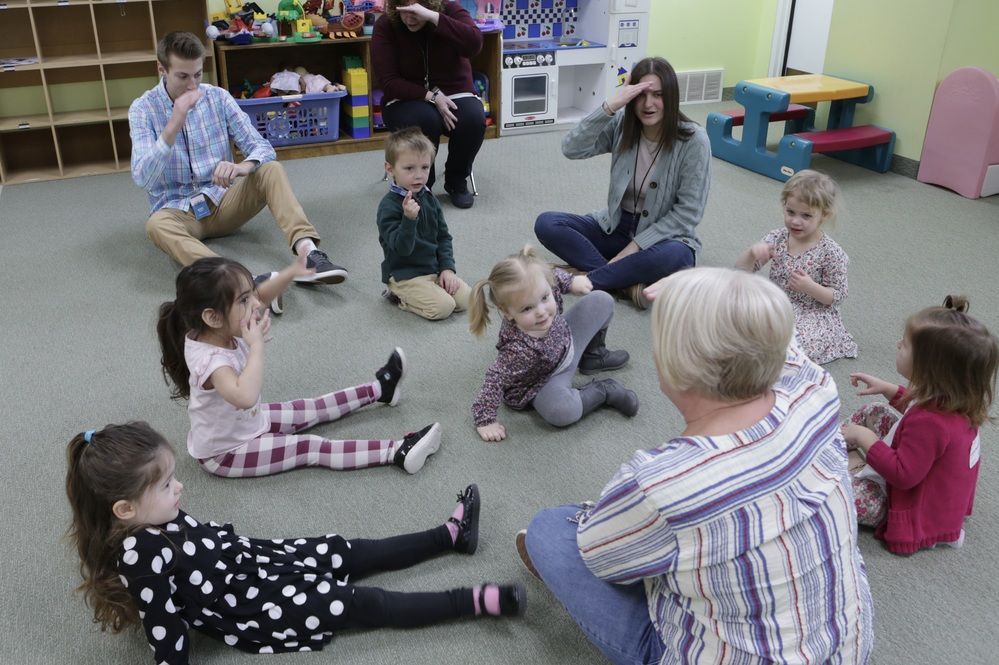 Children and volunteers sitting together in a circle in the GBC Kids room
