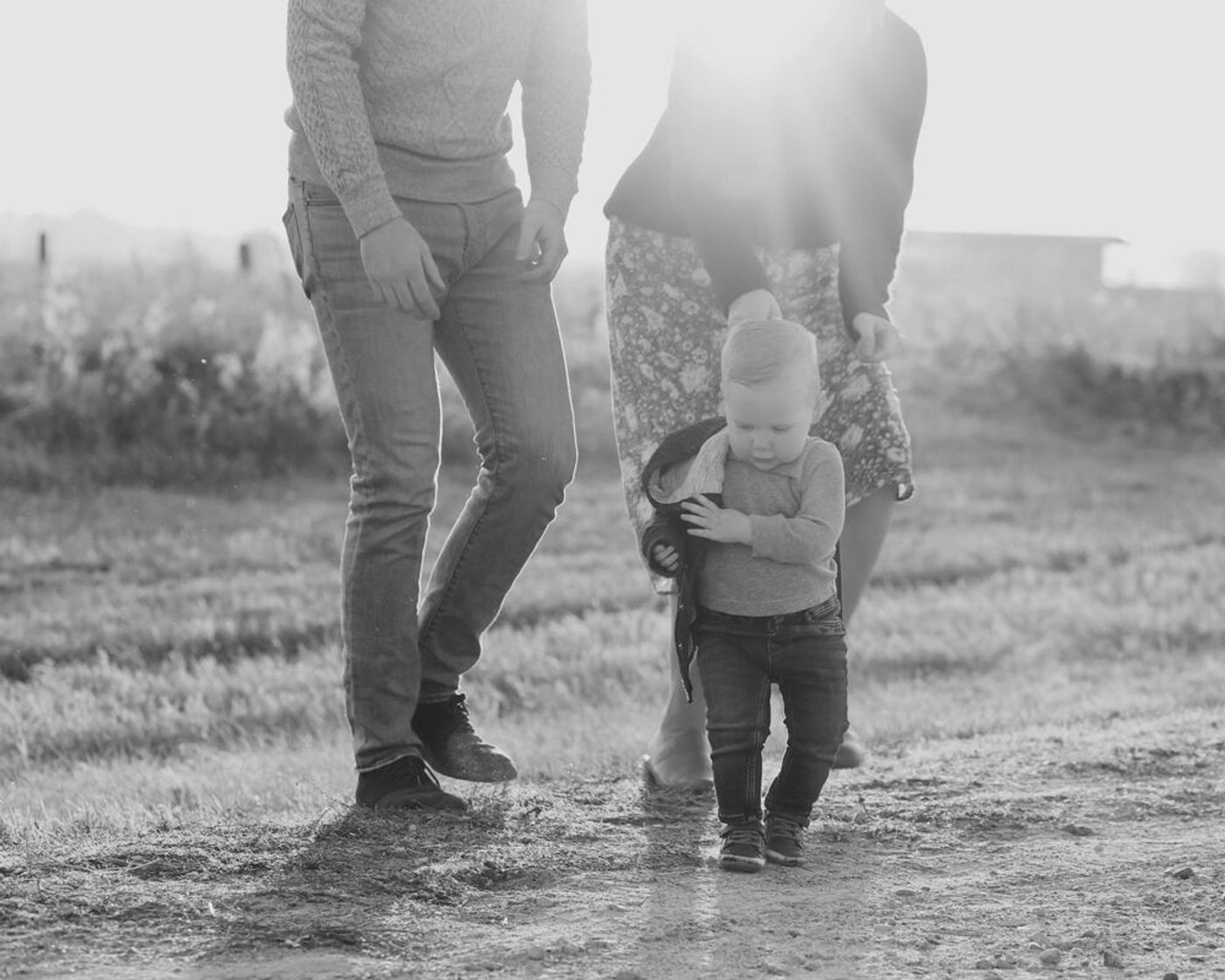 A young family walking together on a sunlit path