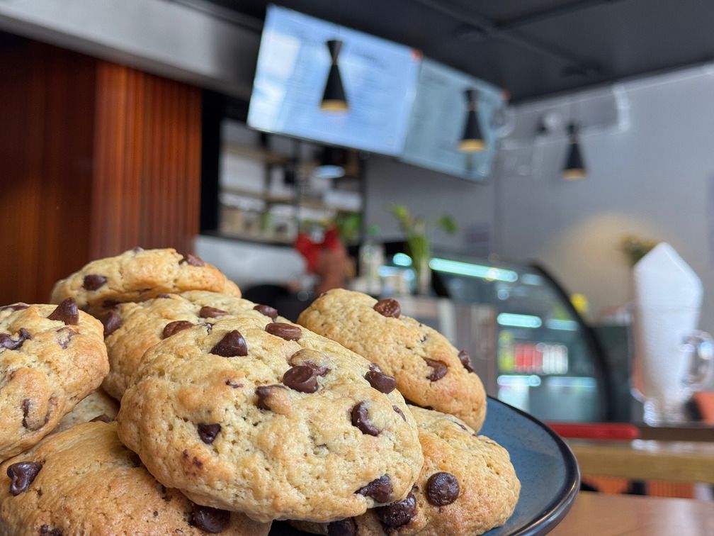 Galletas con chispas de chocolate al frente, mostrador de la cafeteria detras