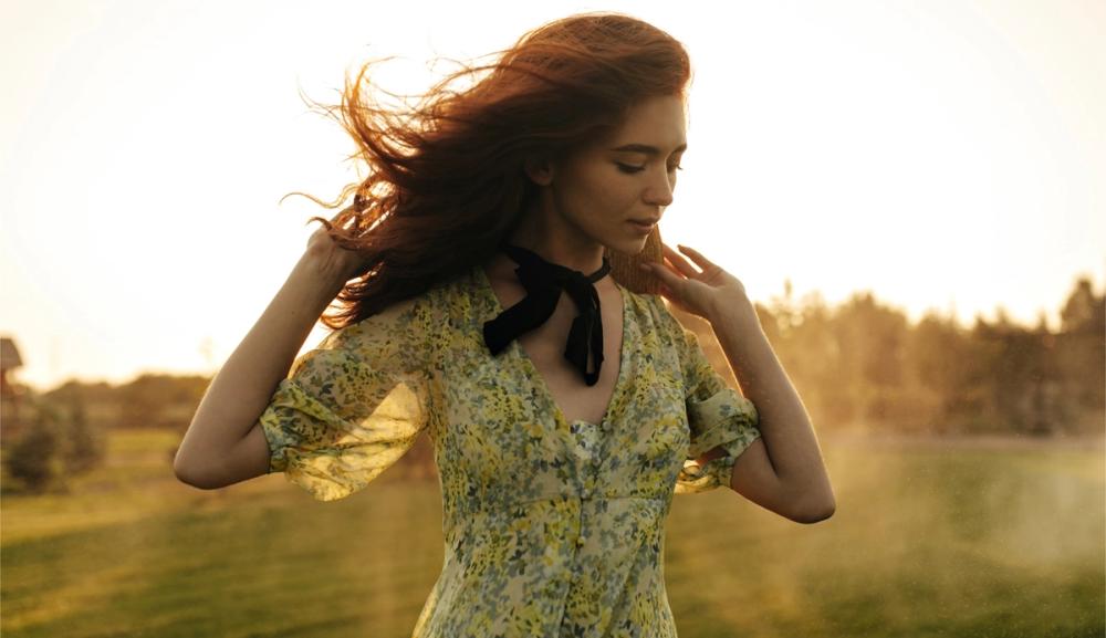 Ung kvinne i eng i kveldssol