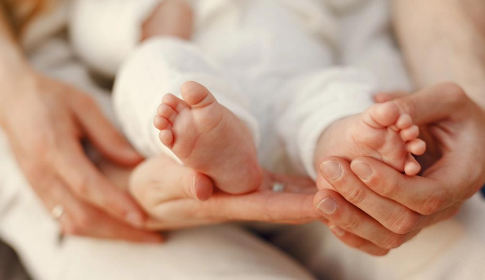 Mors hender holder babyens føtter