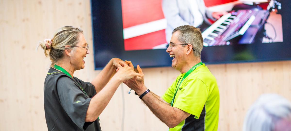 Sangstund på institusjon, mann og kvinne danser og ler