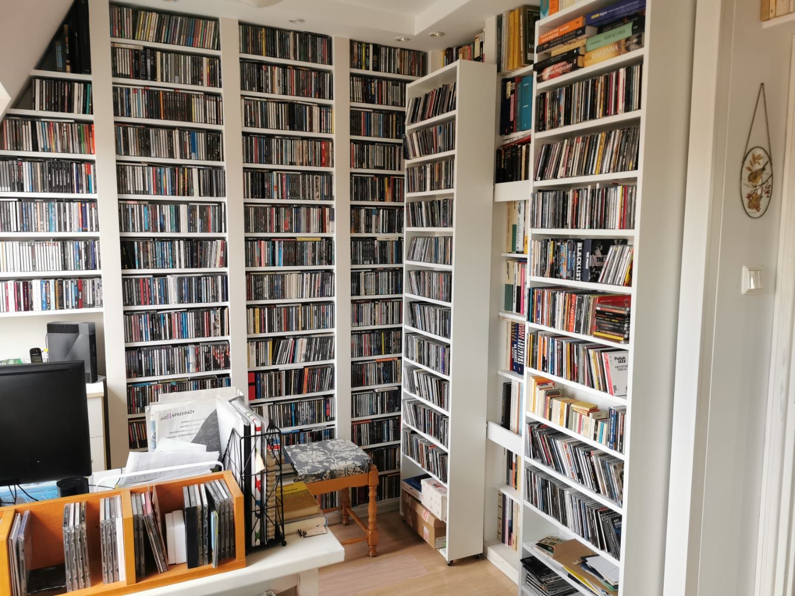 Biblioteka na książki i płyty na całą ścianę i pod skos, białe regały