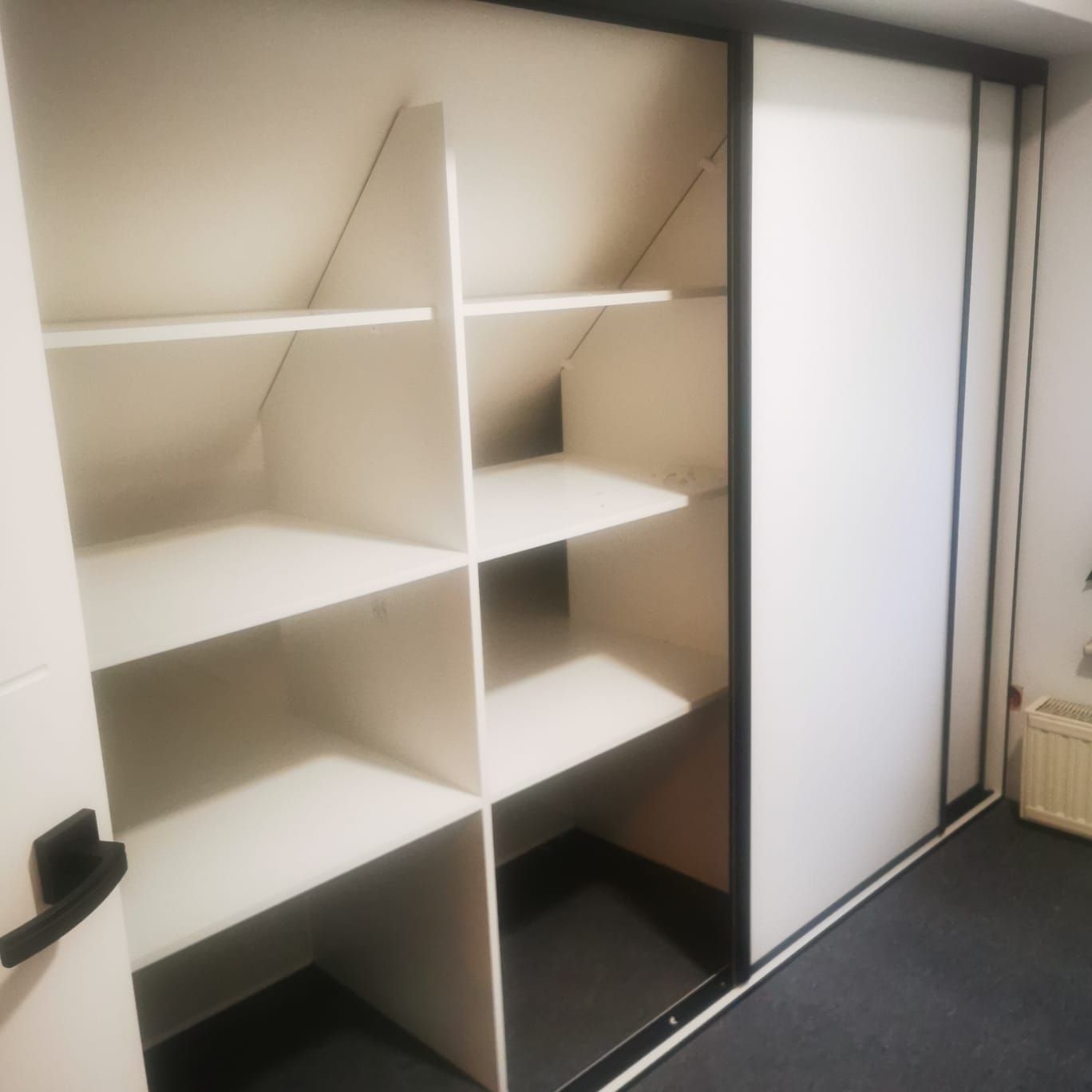Wnętrze szafy pod skos z półkami dopasowanymi do połaci dachu