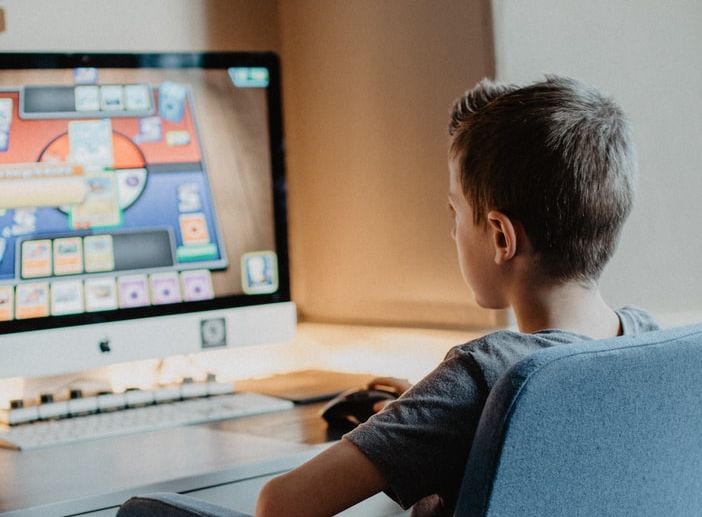 Ein Junge sitzt vor einem Computer und spielt ein Spiel. 