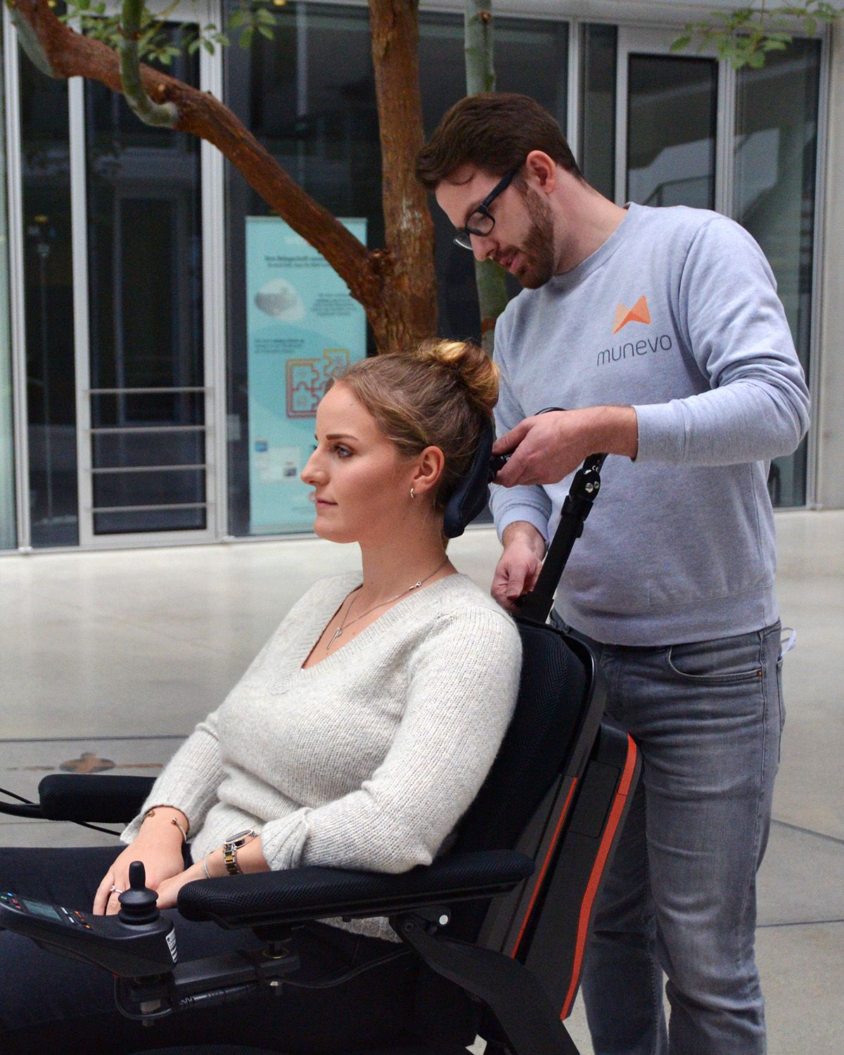 munevo-Mitarbeiter beim Einstellen der Kopfstütze des Rollstuhls einer munevo-Nutzerin