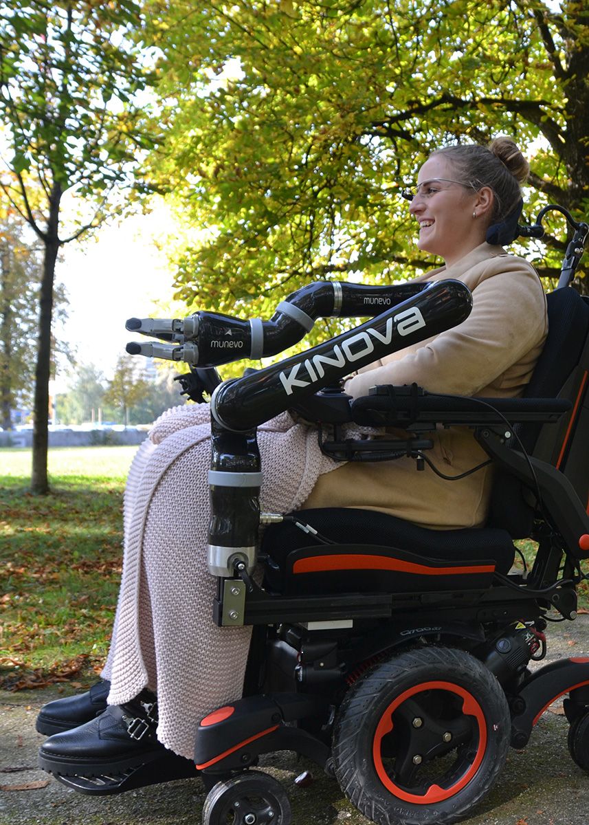 munevo user riding wheelchair outdoors with munevo ARM