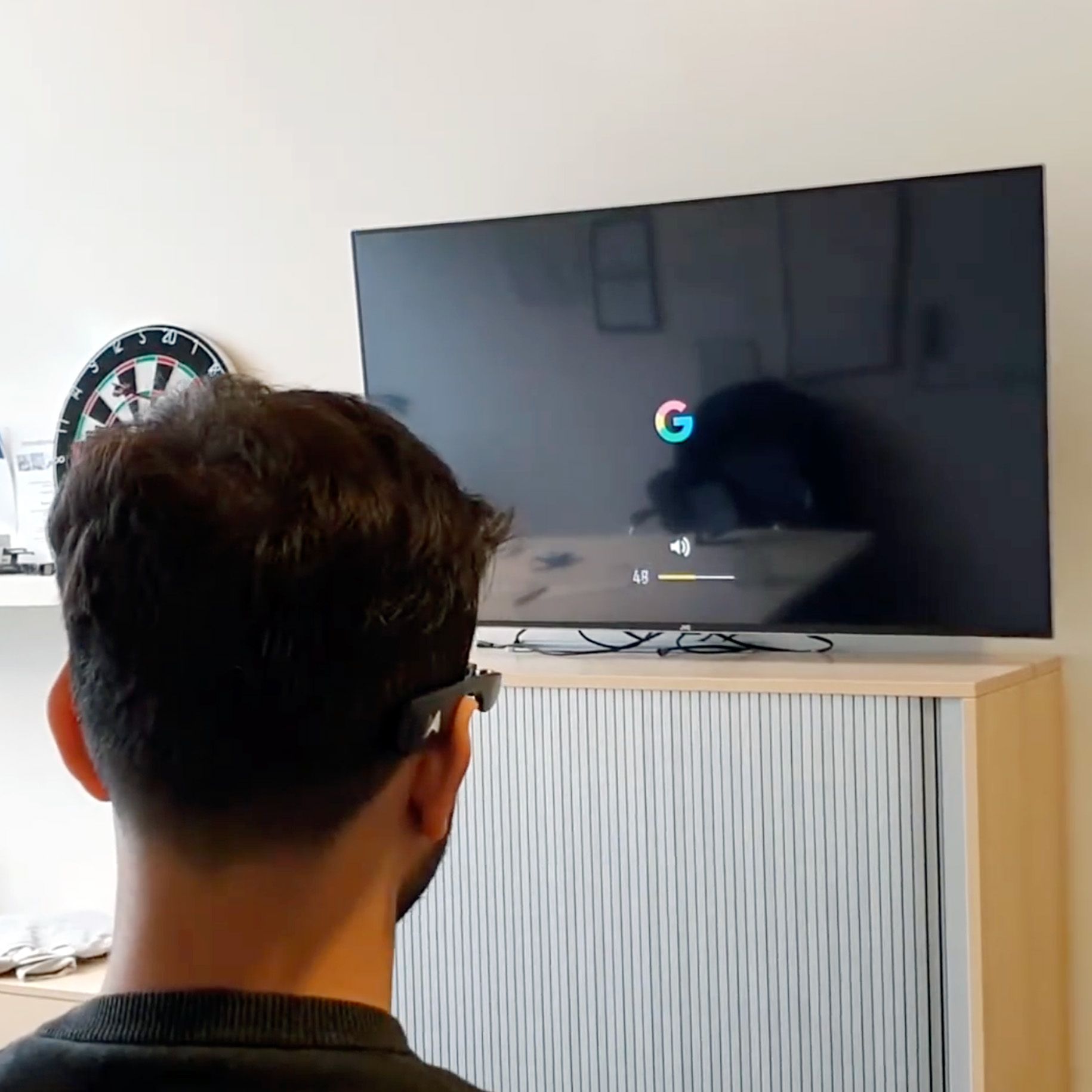 A munevo user turning up the volume of their TV using their smart glasses
